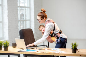 抱っこ紐で赤ちゃんを抱っこしながら仕事をするママ